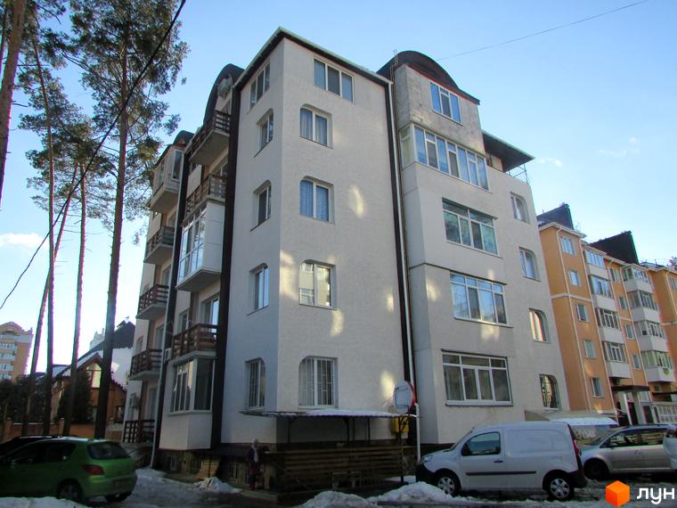 Зовнішній вигляд житлового комплексу Затишний на вул. Університетській. На зображенні видно кілька корпусів новобудови з балконами та вікнами, а також прибудинкову територію з деревами та автомобілями.