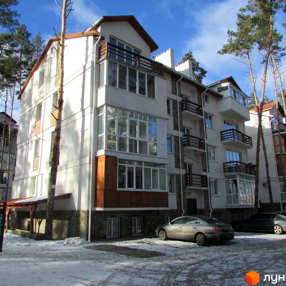 Житловий комплекс Островський: фасади будівель з балконами та великими вікнами, прибудинкова територія з деревами та автомобілями.