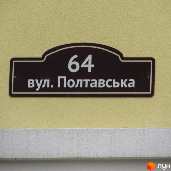Будинок №64 по вулиці Полтавській. Фасад будівлі світло-жовтого кольору з коричневою вивіскою.