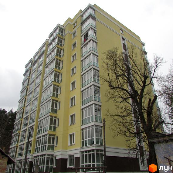 Житловий комплекс Полтавський: жовта багатоповерхівка з численними балконами та великими вікнами. Навколо будівлі видно дерева та елементи прибудинкової території.