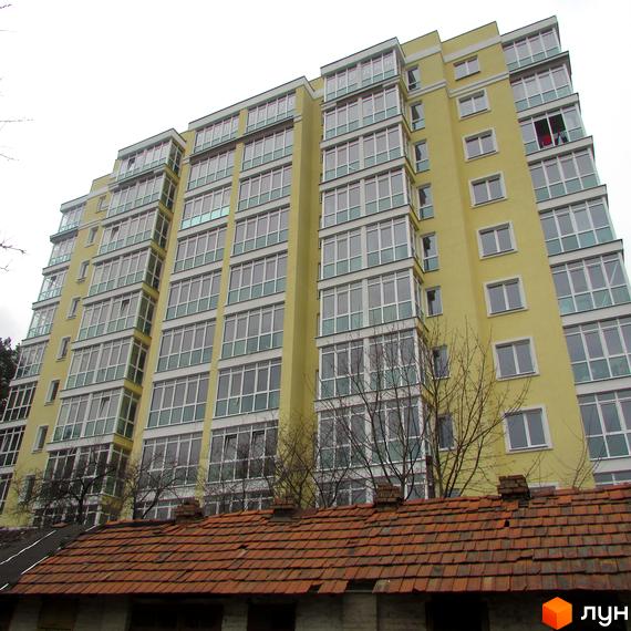 Житловий комплекс Полтавський – жовта багатоповерхівка з численними вікнами та балконами. На передньому плані видно дах старої будівлі.