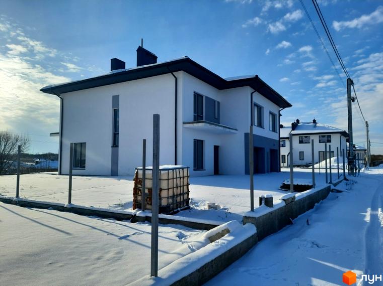 Двоповерховий білий будинок Котеджного містечка ЗУБРА ETALON з сірими акцентами на фасаді. Прибудинкова територія вкрита снігом, видно елементи забудови.