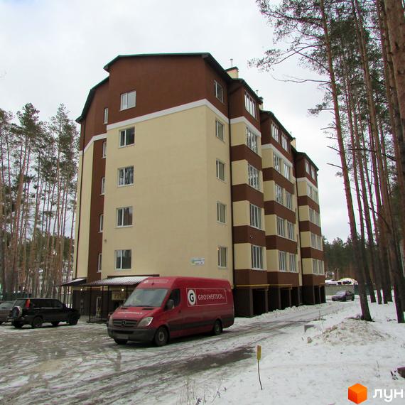 Житловий комплекс Matroskin: багатоповерховий будинок з коричневими та світлими фасадами, розташований серед засніжених сосен.