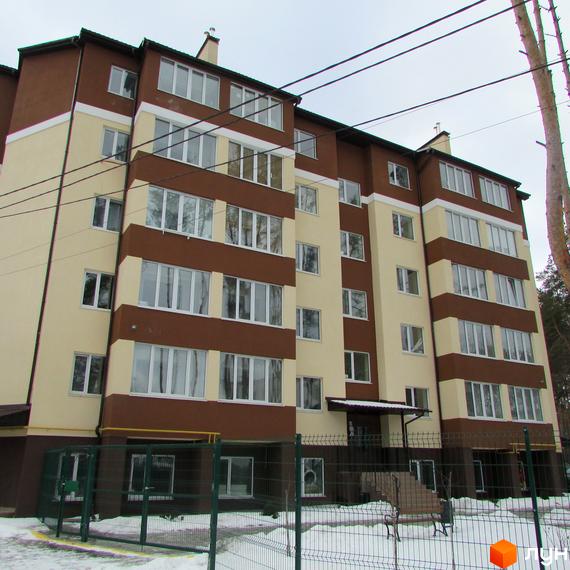 Багатоповерховий будинок Житлового комплексу Matroskin з коричнево-бежевим фасадом та великими вікнами. Прибудинкова територія огороджена, вкрита снігом.