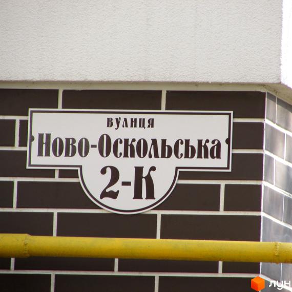 Фасад новобудови Затишний, облицьований темно-коричневою плиткою, з табличкою вулиці Ново-Оскольська 2-К.