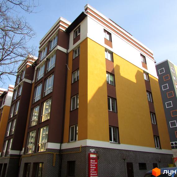 Багатоповерховий житловий будинок Новобудови Затишний з коричневими та жовтими фасадами, білими архітектурними елементами та цегляною основою.