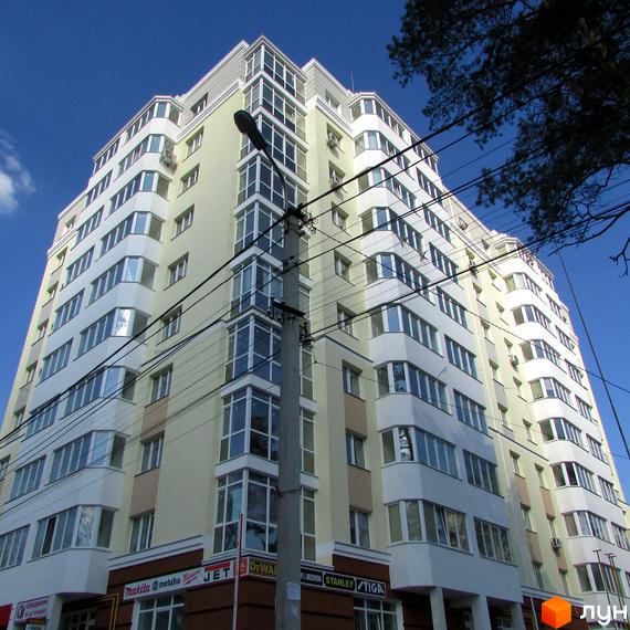 Зовнішній вигляд новобудови ЖК Капітал з багатьма вікнами та балконами. Будинок має світло-жовтий фасад з білими елементами.
