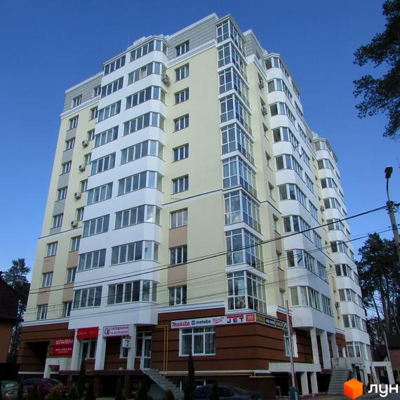 Зовнішній вигляд багатоповерхового будинку ЖК Капітал з великою кількістю вікон та балконів. На першому поверсі розташовані комерційні приміщення. Навколо будинку видно дерева та елементи прибудинкової території.