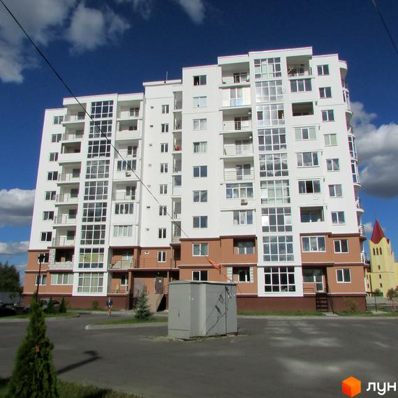 Новобудова ЖК Вишиванка - це багатоповерховий будинок білого кольору з коричневим цоколем та численними балконами. Навколо будинку розташована прибудинкова територія з зеленими насадженнями та парковкою.