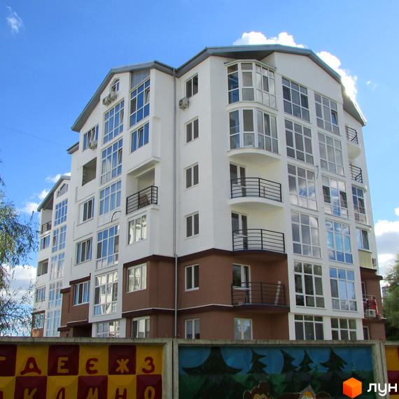 Житловий комплекс Вишиванка. Зовнішній вигляд новобудови з великою кількістю вікон та балконів. На передньому плані огорожа з малюнками.