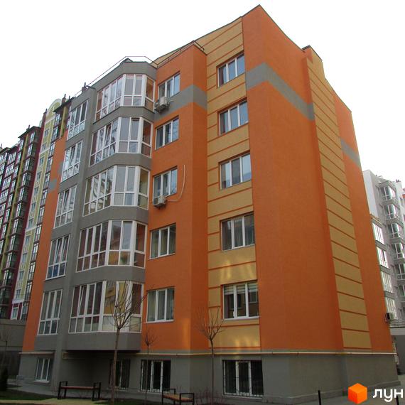 Житловий комплекс Status – багатоповерховий будинок з яскравим фасадом у помаранчевих та сірих тонах. Навколо будинку облаштована прибудинкова територія з лавками та деревами.