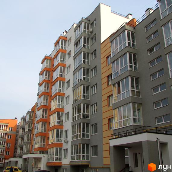 Житловий комплекс Status: фасади будинків з панорамним склінням та балконами. Зовнішній вигляд новобудови з елементами помаранчевого та сірого кольору.