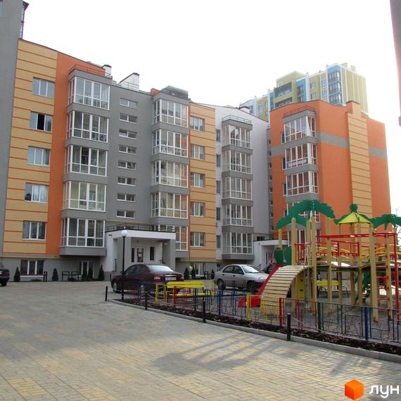 Житловий комплекс Status: фасади будівель з панорамним склінням та дитячий майданчик на прибудинковій території. Фото новобудови.