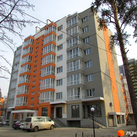 Зовнішній вигляд новобудови ЖК Status: багатоповерховий будинок з помаранчевими та сірими фасадами, великими вікнами. Перед будинком розташована прибудинкова територія з автомобілями та деревами.