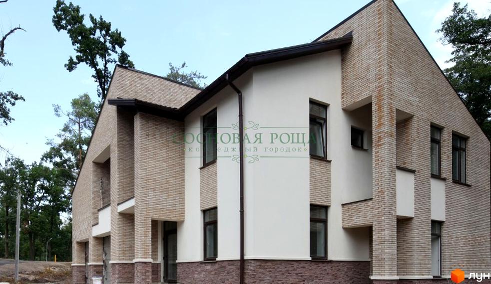 Будинок Котеджного містечка Соснова роща з фасадом з цегли та білою штукатуркою. Поруч дерева та блакитне небо.