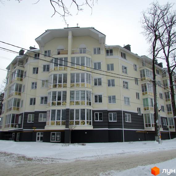 Багатоповерховий будинок житлового комплексу Аристократ з панорамними вікнами та балконами. Навколо будинку сніг та дерева.