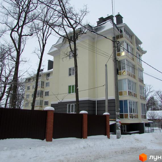 Багатоповерховий будинок ЖК Аристократ з панорамними вікнами та балконами. Навколо будинку засніжена прибудинкова територія та паркан.