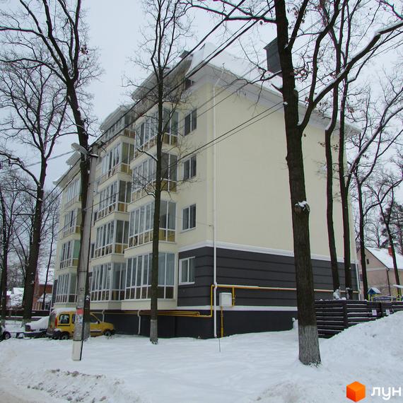 Зображення житлового комплексу Аристократ. Багатоповерховий будинок з панорамними вікнами та світлим фасадом. Навколо будинку сніг та дерева.