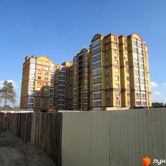 Висотна будівля Житлового комплексу Центральний з великою кількістю вікон. Поруч розташований паркан та небо.