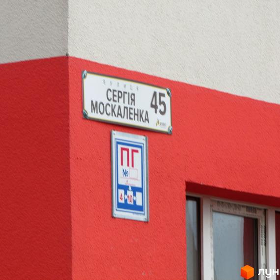 Червоний будинок з білою стіною, на якій висить табличка з назвою вулиці Сергія Москаленка та номером 45. Поряд розташована табличка з позначенням ПГ.