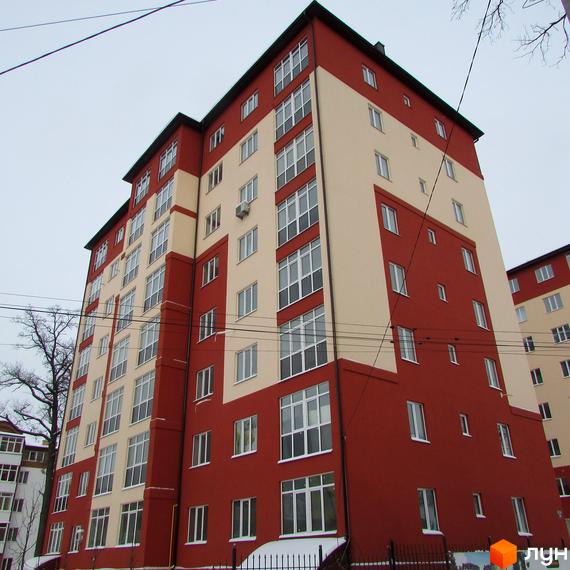 Багатоповерховий будинок ЖК Green Life з фасадом у червоних та бежевих тонах. На території є ковані огорожі та дерева.