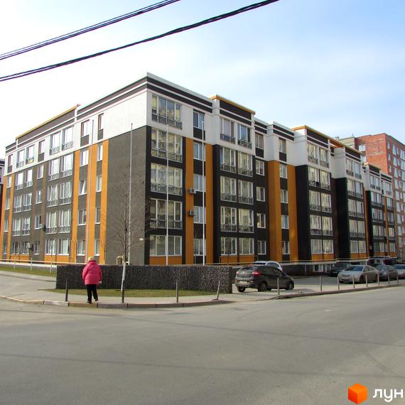 Житловий комплекс Фортуна-2 з фасадом у чорно-жовтих тонах. На території комплексу є парковка для автомобілів та зелені насадження.