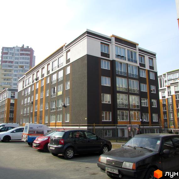 Житловий комплекс Фортуна-2. Багатоповерховий будинок з темним фасадом та білими вікнами. На передньому плані парковка з автомобілями.