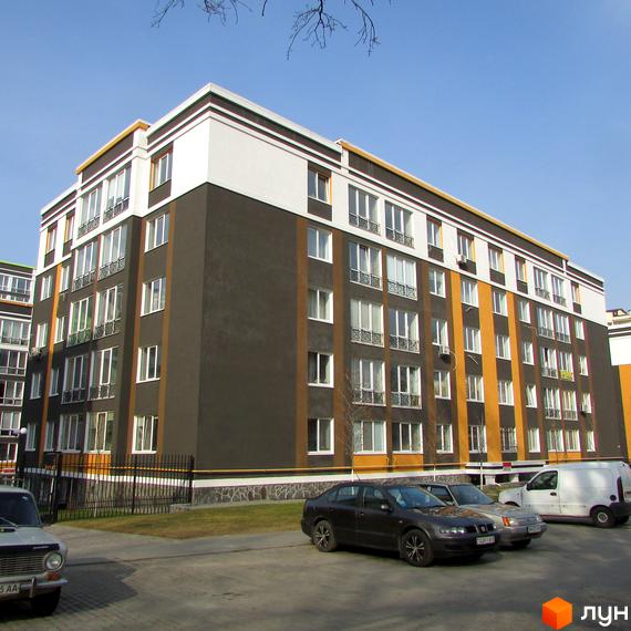 Житловий комплекс Фортуна-2 з фасадом у коричневих та білих тонах. На прибудинковій території є парковка з автомобілями.