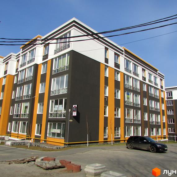 Житловий комплекс Фортуна-2. Багатоповерховий будинок з великими вікнами та яскравим фасадом. На території є парковка та невелика прибудинкова зона.