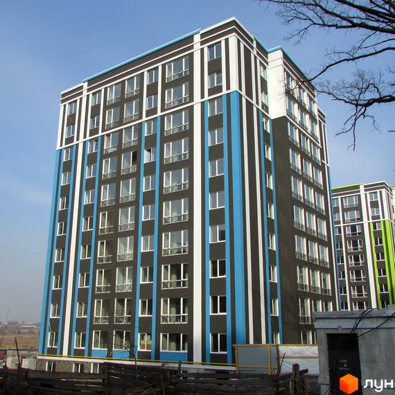 Висотна новобудова ЖК Фортуна-2 з фасадом у смужку. На передньому плані видно огорожу та будівельні матеріали.