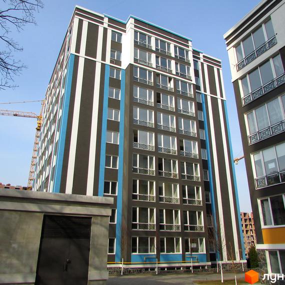 Висотна будівля ЖК Фортуна-2 з великою кількістю вікон та смугастим фасадом. На території є зелені насадження та будівлі.