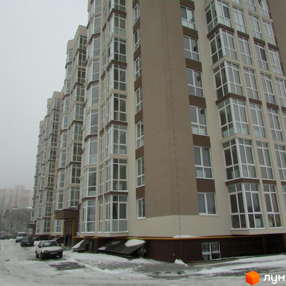 Висотна будівля ЖК Ярославський з великою кількістю вікон. На передньому плані сніг та прибудинкова територія.