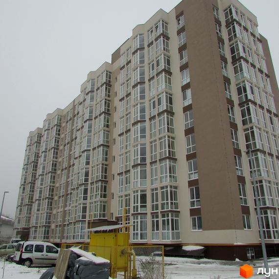 Висотна будівля ЖК Ярославський з великою кількістю вікон. На території сніг, поруч припарковані автомобілі.