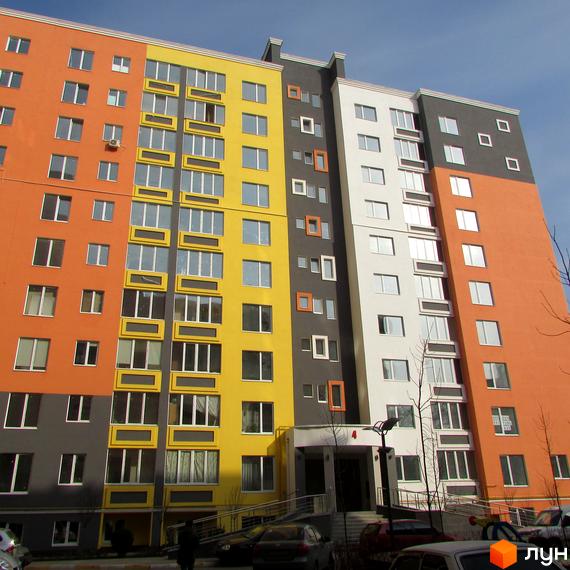 Яскрава багатоповерхівка ЖК Синергія-2 з різнокольоровим фасадом. Перед будинком розташована прибудинкова територія з паркуванням.