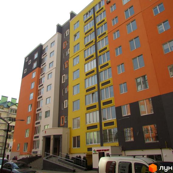 Багатоповерховий будинок ЖК Синергія-2 з яскравим фасадом. На прибудинковій території є парковка та зелені насадження.