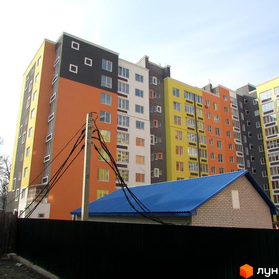 Багатоповерховий будинок Житлового комплексу Синергія-2 з яскравим фасадом. Поруч знаходиться будівля з синім дахом.