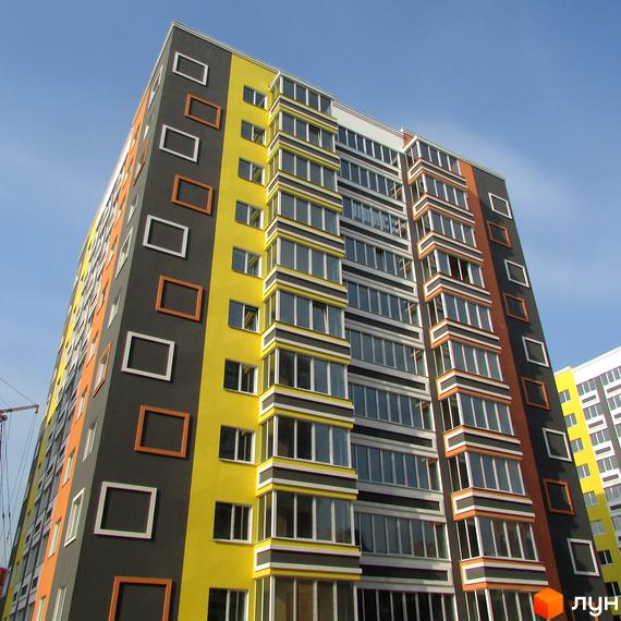 Багатоповерхова новобудова ЖК Синергія-2 з яскравим фасадом та панорамними вікнами. Навколо будинку блакитне небо.