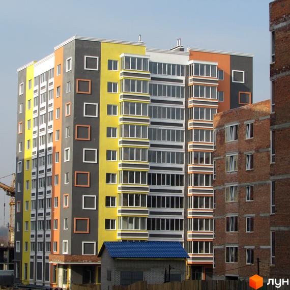Багатоповерховий будинок житлового комплексу Синергія-2 з яскравим фасадом. Поруч розташовані інші будинки та будівельний кран.