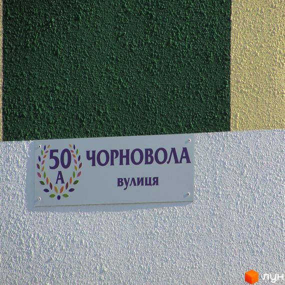 Фасад будинку за адресою Чорновола, 50. На стіні табличка з назвою вулиці та номером будинку у Житловому комплексі Чорновола.