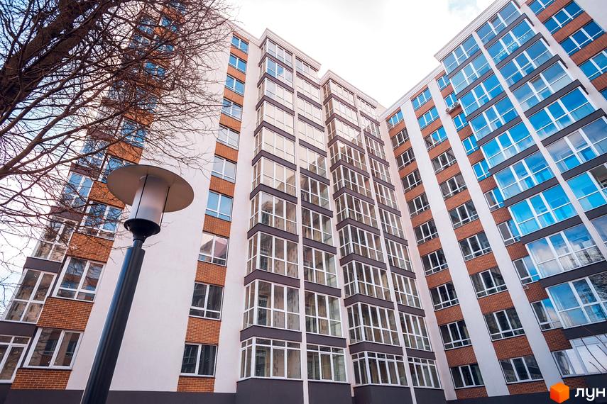 Фасад житлового комплексу Акварель-4 з цегляними вставками та великими вікнами. Зовнішній вигляд новобудови, що демонструє архітектурні рішення.