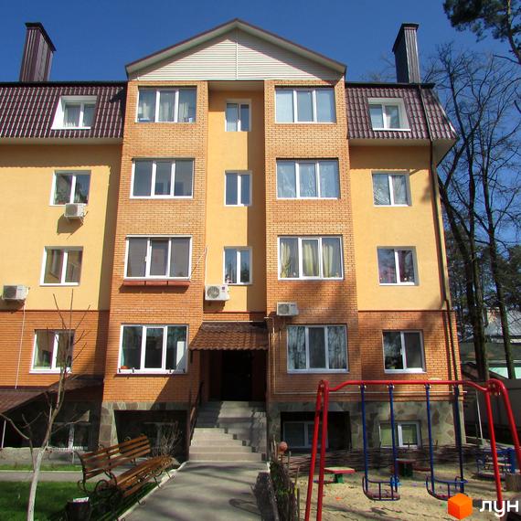 Житловий комплекс на вул. Полтавська, 31е, 31з. Багатоповерховий будинок з жовтою та цегляною обробкою, вікнами та кондиціонерами. На прибудинковій території розташовані лавка та дитячий майданчик з гойдалками.