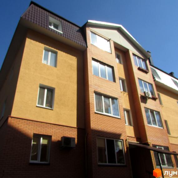 Фасад житлового комплексу на вул. Полтавська, 31е, 31з. Будинок цегляний з жовтою штукатуркою та коричневим дахом.