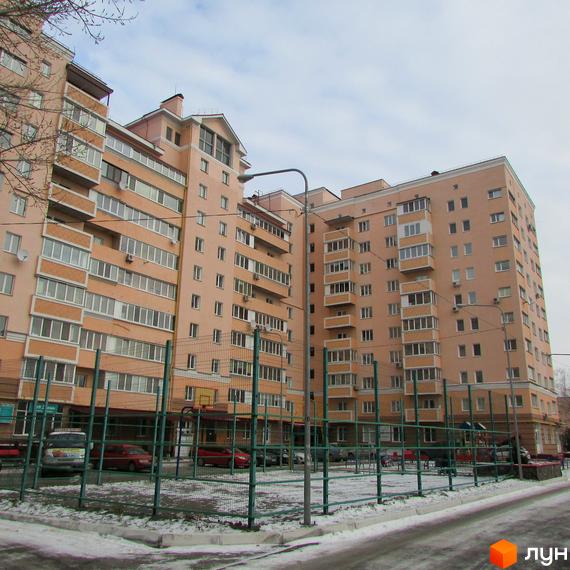 Зовнішній вигляд багатоповерхового житлового комплексу просп. Шевченка, 6а, з балконами та великою кількістю вікон. На прибудинковій території розташований спортивний майданчик.