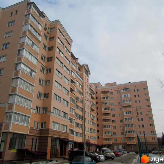 Зовнішній вигляд житлового комплексу на просп. Шевченка, 6а. Багатоповерхові будинки світло-персикового кольору з численними вікнами та балконами. Біля будинку розташована прибудинкова територія з автомобілями та деревами.