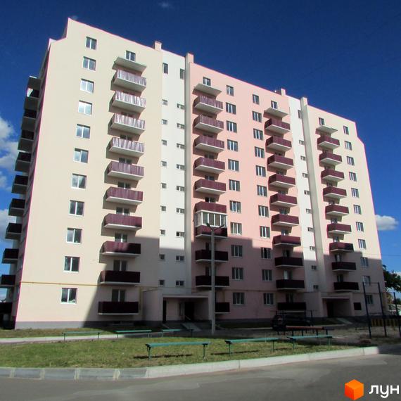 Зовнішній вигляд багатоповерхового житлового комплексу Нове Життя з балконами та вікнами. Навколо будинку зелена зона з лавками та доріжками.