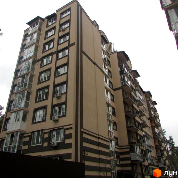 Зовнішній вигляд житлового комплексу Котляревського: висотна будівля з балконами та кондиціонерами, оздоблена бежевими та темними смугами. Навколо видно дерева та паркан.