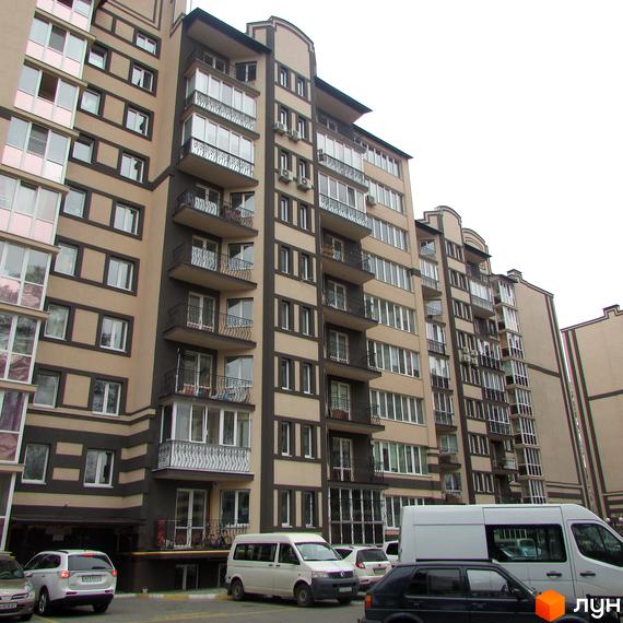 Зовнішній вигляд багатоповерхового житлового комплексу Котляревського з балконами та кондиціонерами. Прибудинкова територія з автомобілями та мінівенами.