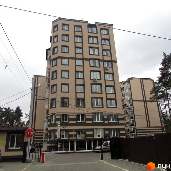 Зовнішній вигляд багатоповерхового житлового комплексу Котляревського з бежевим фасадом та темними декоративними елементами. На прибудинковій території видно шлагбаум та охоронний пост.