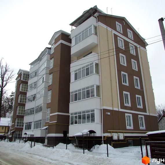 Житловий комплекс Надсонов – багатоповерховий будинок з коричнево-бежевим фасадом та білими балконами. Навколо будівлі видно засніжену територію та паркан.