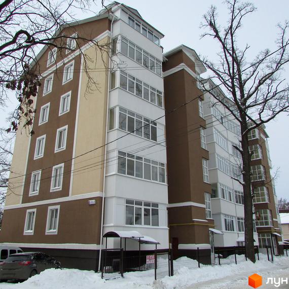 Житловий комплекс Надсонов. Зовнішній вигляд будинку з коричнево-білими фасадами та заскленими балконами. Навколо будівлі видно засніжену територію та дерева.